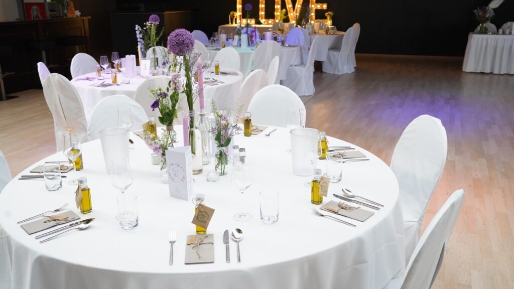 Eine Hochzeitslocation mit eleganten Tischen und Stühlen für eine Hochzeitsfeier.